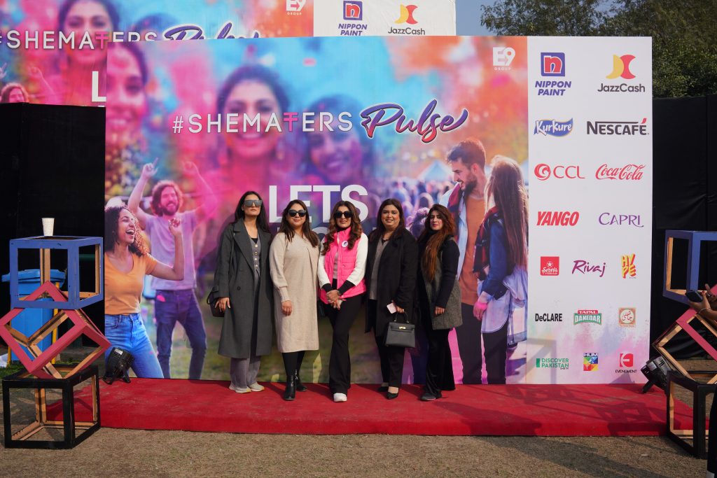 A group of women standing in front of a colourful SheMatters Pulse event backdrop.