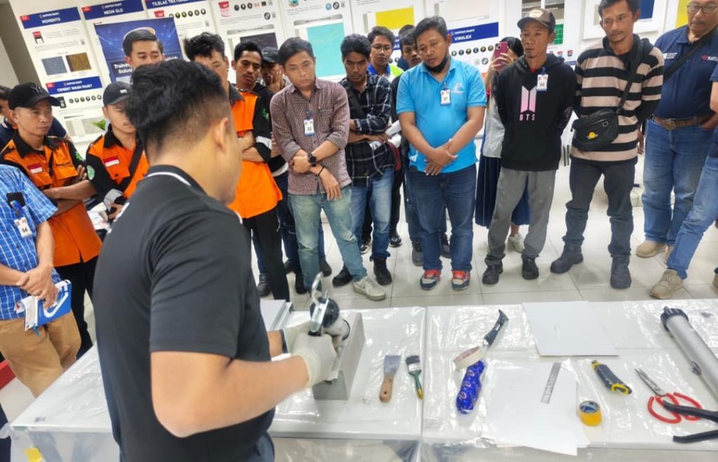A trainer demonstrating sealant application techniques to a focused group of professional applicators at a V-tech training session.