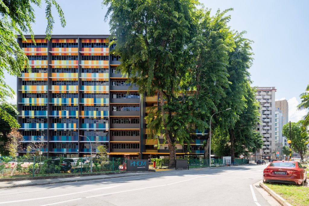 A wide exterior view of the HHOM Nurse Hostel building featuring a brightly coloured, multi-story facade.