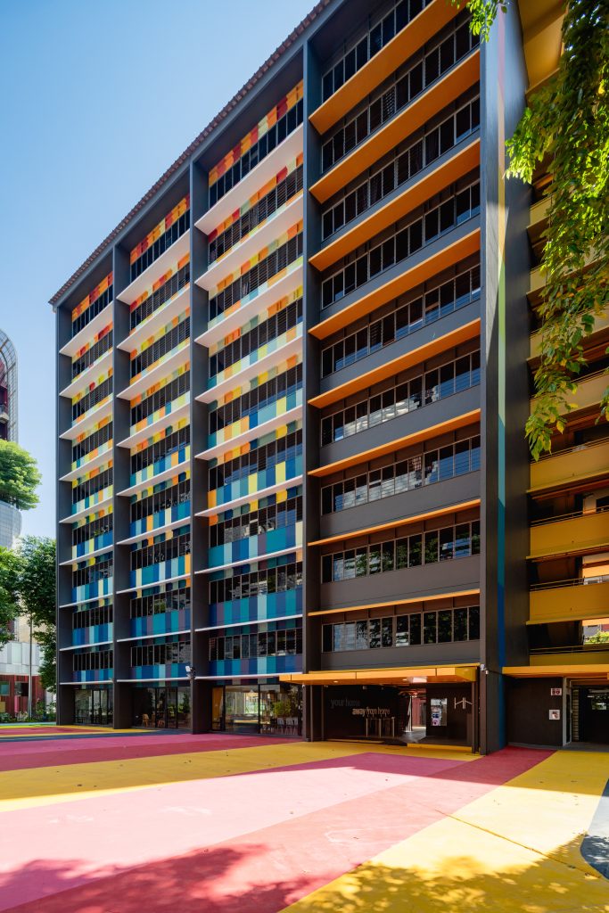 An angled shot of the HHOM Nurse Hostel highlighting the colourful window ledges and the dark grey building structure.