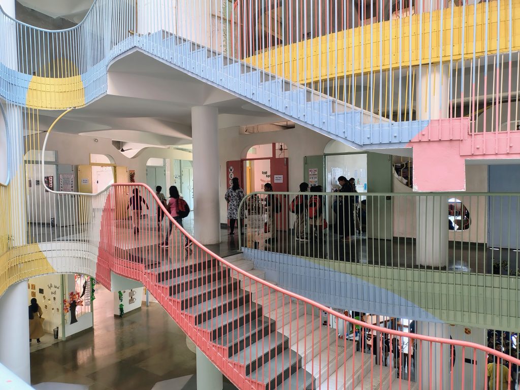 Multi-level curved walkways and staircases lined with pastel yellow, blue, and red railings.