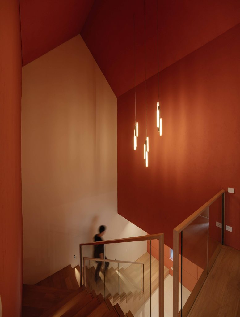 A striking double-height stairwell painted entirely in deep International Orange paint.