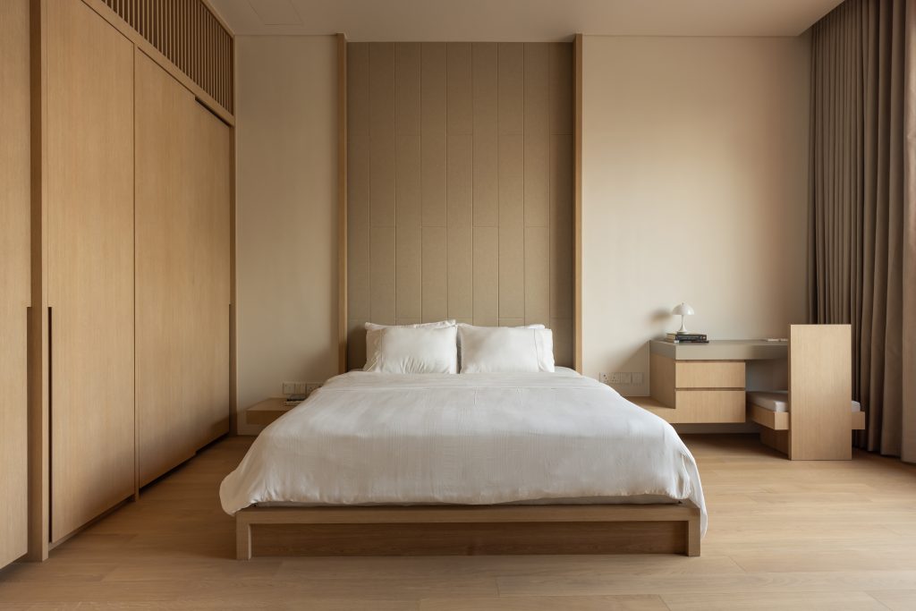 A minimalist bedroom with a light timber bed frame and matching wardrobes.
