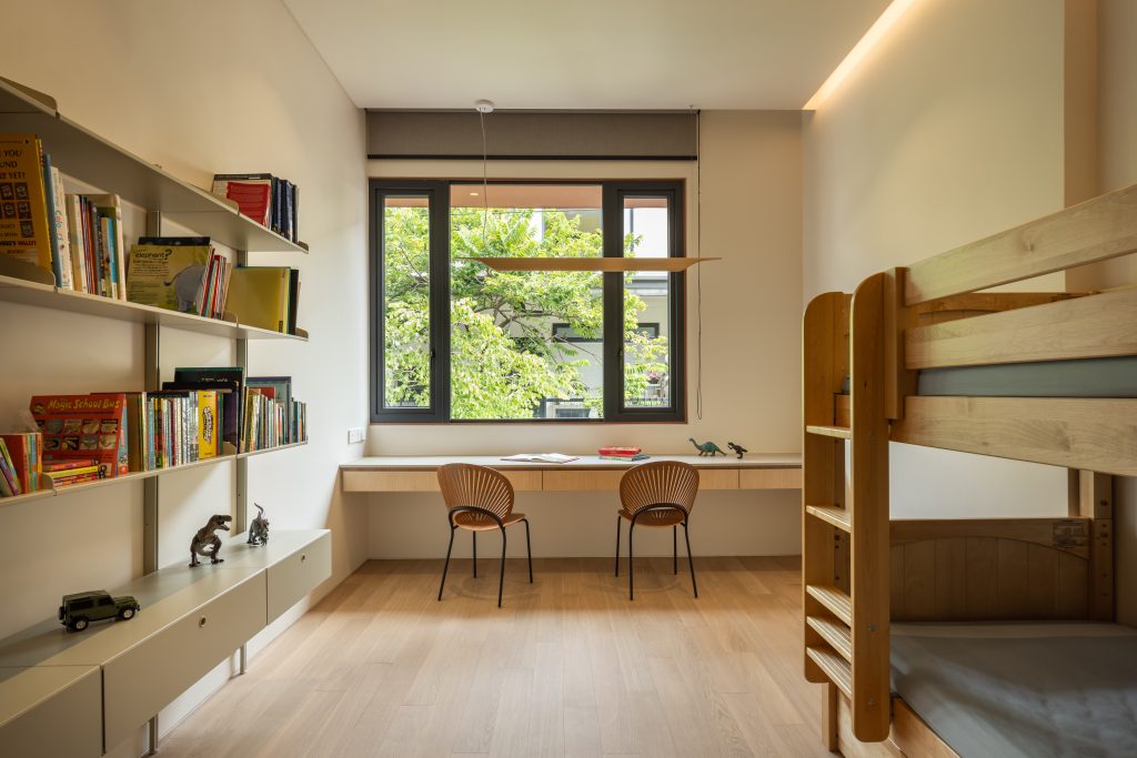 A children's bedroom featuring a wooden bunk bed and a long study desk.