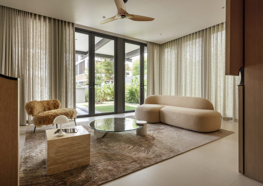 A bright, neutral living room featuring a textured rug and curved sofa.