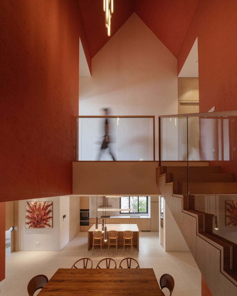 A view looking down from the orange stairwell into a bright, neutral kitchen.