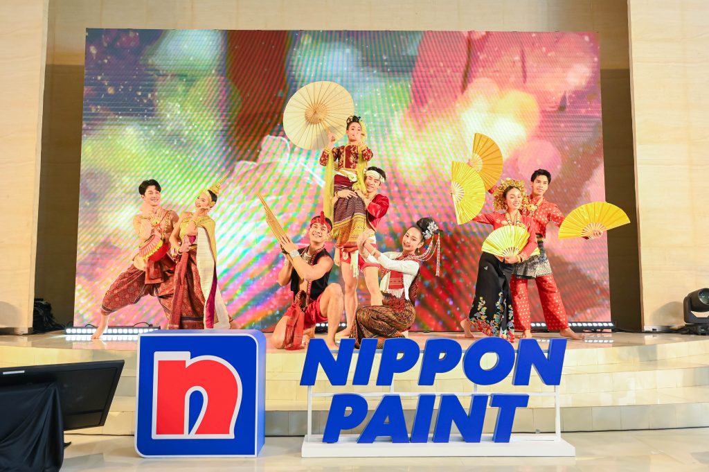 Performers in traditional Thai attire dancing with fans on stage during the opening ceremony.