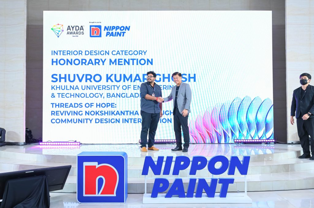 Shuvro Kumar Ghosh smiling and shaking hands with Mr Wee Siew Kim on the awards stage.
