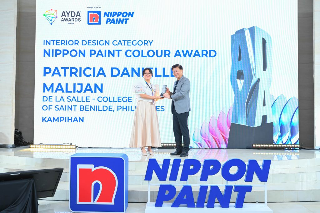 Patricia Danielle Malijan smiling as she receives her award trophy on stage from Mr Wee Siew Kim.