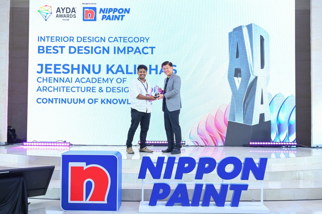 Jeeshnu Kalidhas shaking hands and accepting his award trophy from Mr Wee Siew Kim on stage.