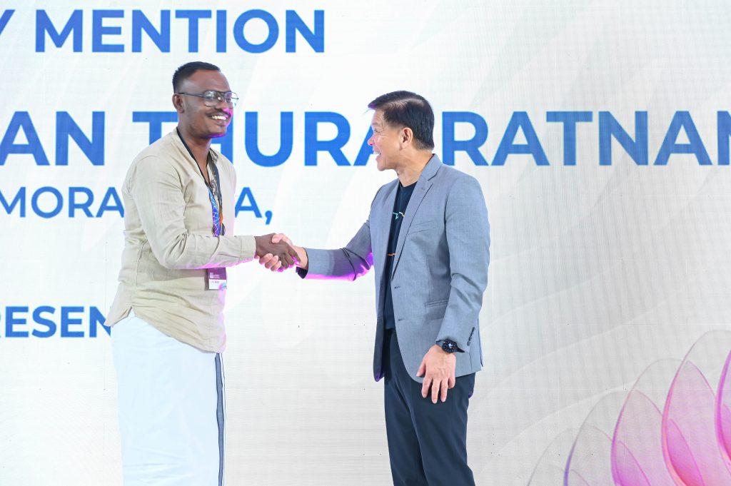Pavithran Thurairatnam grins while shaking hands with Mr Wee Siew Kim on the main stage.
