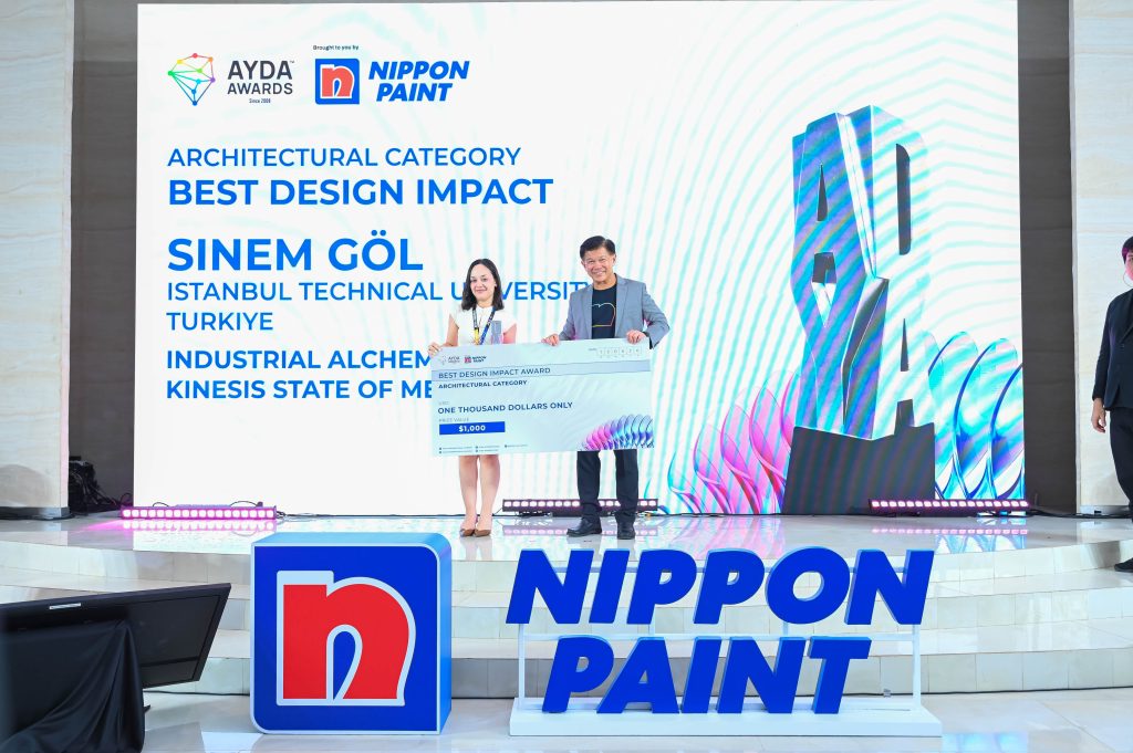 Sinem Göl stands on stage holding a USD 1,000 category prize cheque next to Mr Wee Siew Kim.