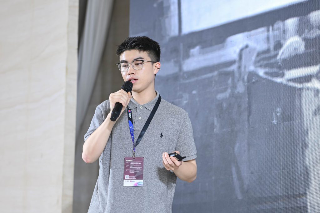 Jackie Jiang Haoran standing on stage with a microphone, confidently presenting his design project to the audience.