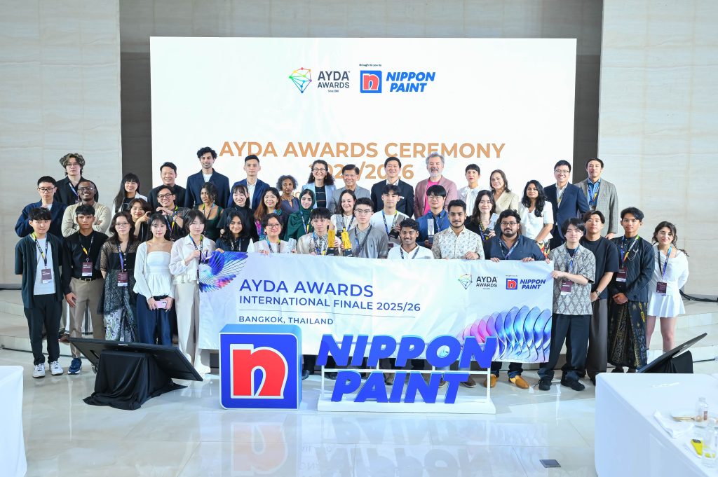 A large group photograph of all AYDA Awards participants, judges, and leaders standing together behind an event banner on stage.