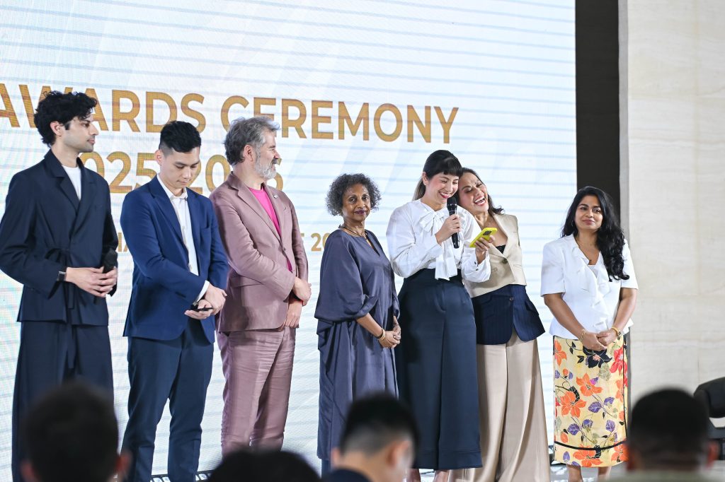 The judging panel standing together on stage, smiling and laughing during the awards ceremony.