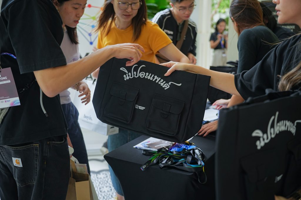 Participants collecting black Nippon Paint tote bags at the AYDA registration counter.