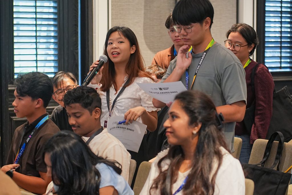A female participant standing up to share her thoughts using a microphone during a session.