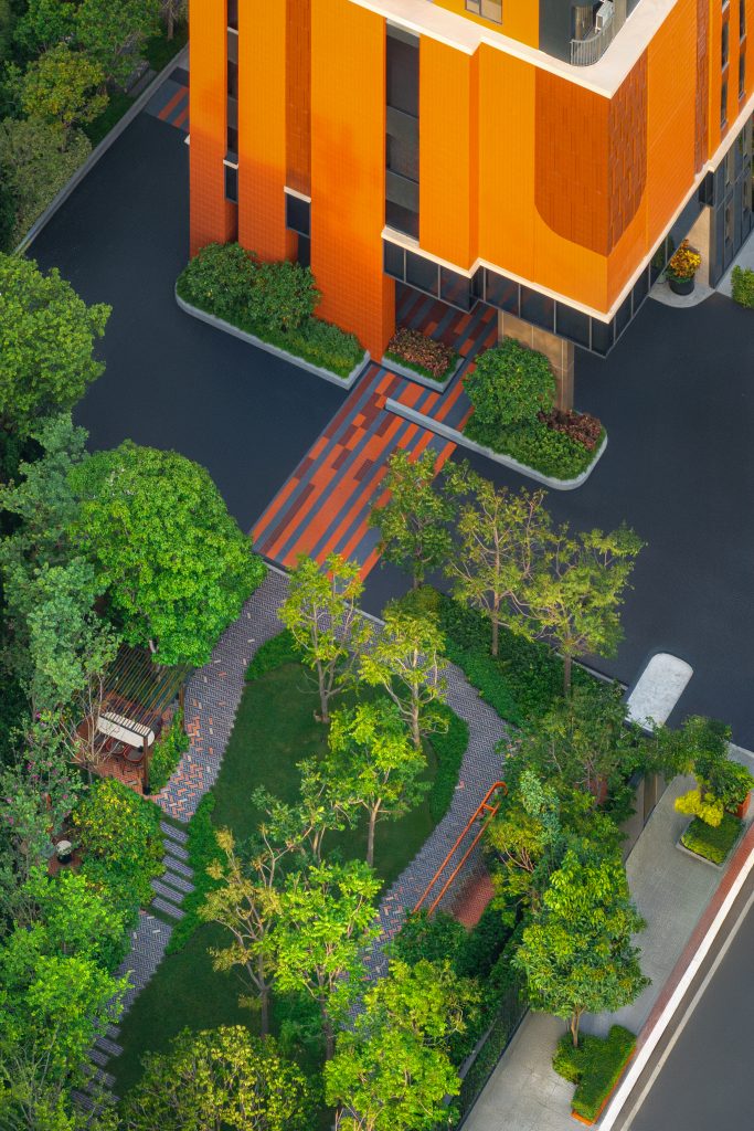 A top-down aerial view of the building's rooftop pool, orange spiral staircase, and lush green lounging area.
