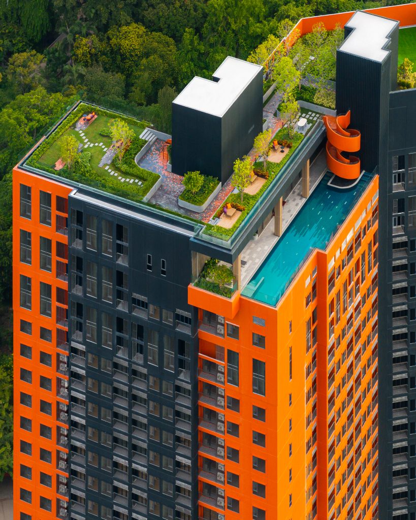 An aerial view of the ground floor park at Flo by Sansiri, showcasing green spaces and brick-patterned pathways.