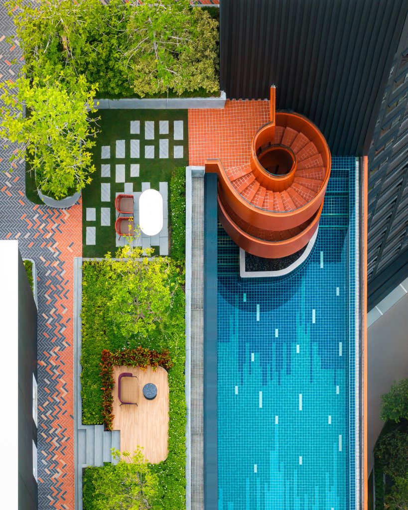 The upper levels of the Flo condominium, featuring a rooftop swimming pool, garden, and a distinctive orange spiral staircase.