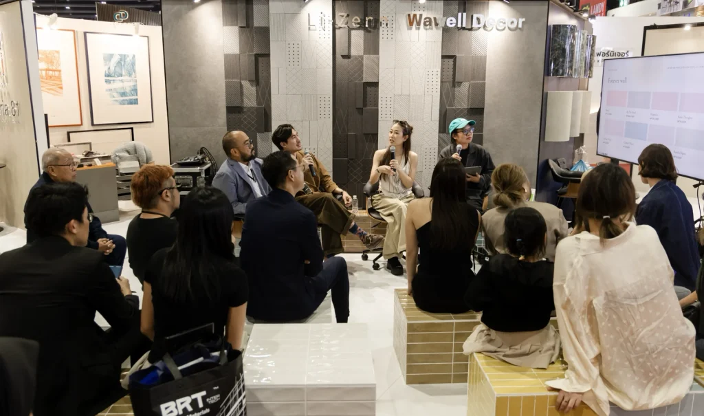 A panel of speakers sits on stage addressing an attentive audience at a design event.