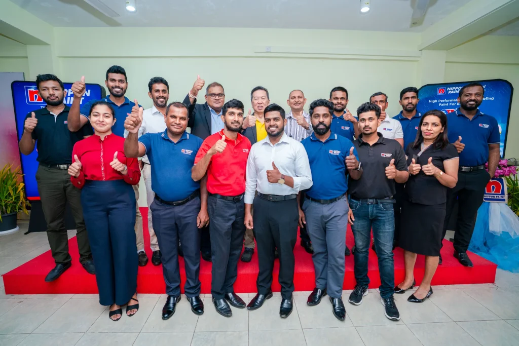 A group of professional painters and academy executives give a thumbs up on stage.
