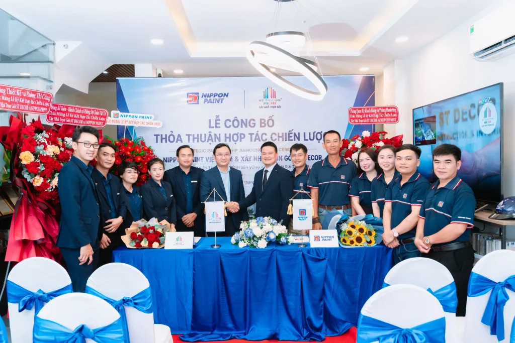 Two executives and their teams stand together after signing a partnership agreement.