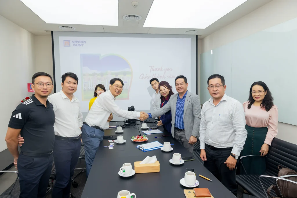 Business professionals stand around a conference table after a successful presentation.