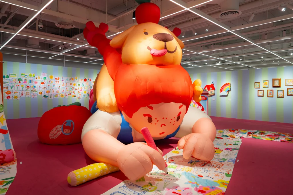 A massive inflatable sculpture of a girl drawing with a dog on her back.