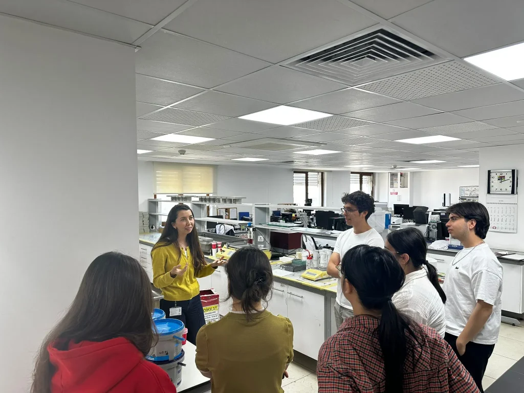 A female instructor explains laboratory processes to a group of university students.