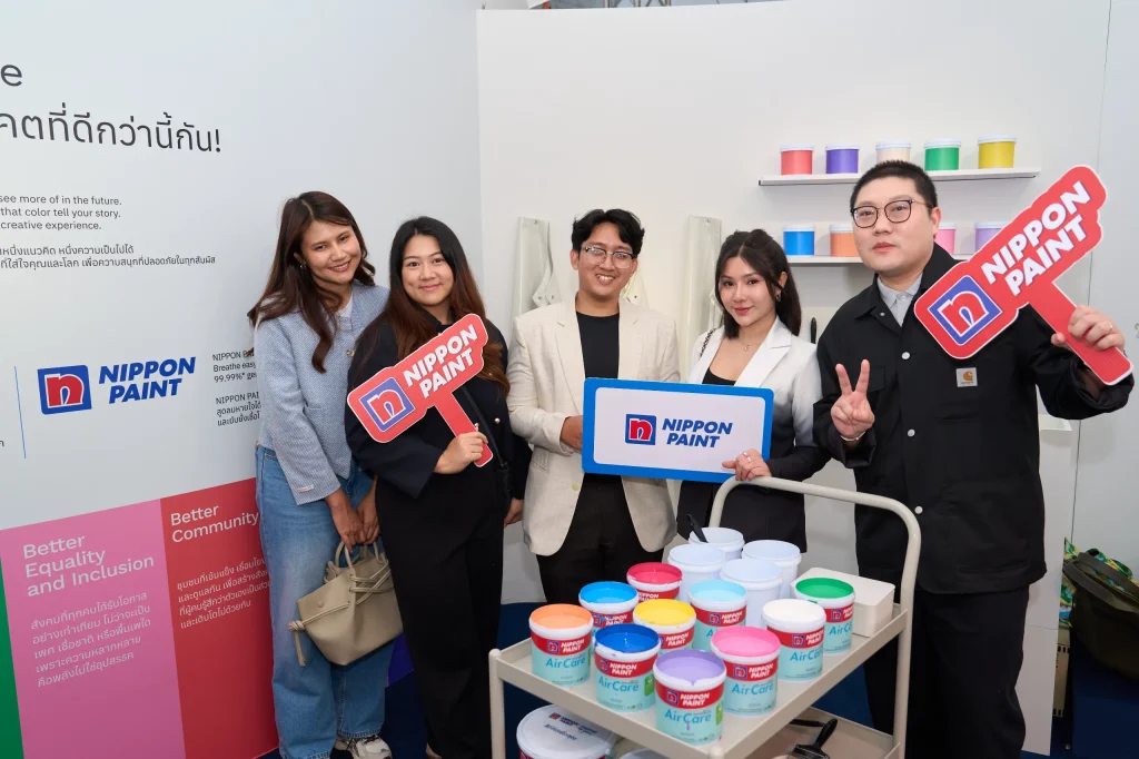Five attendees pose happily with Nippon Paint signs next to a colourful paint trolley.